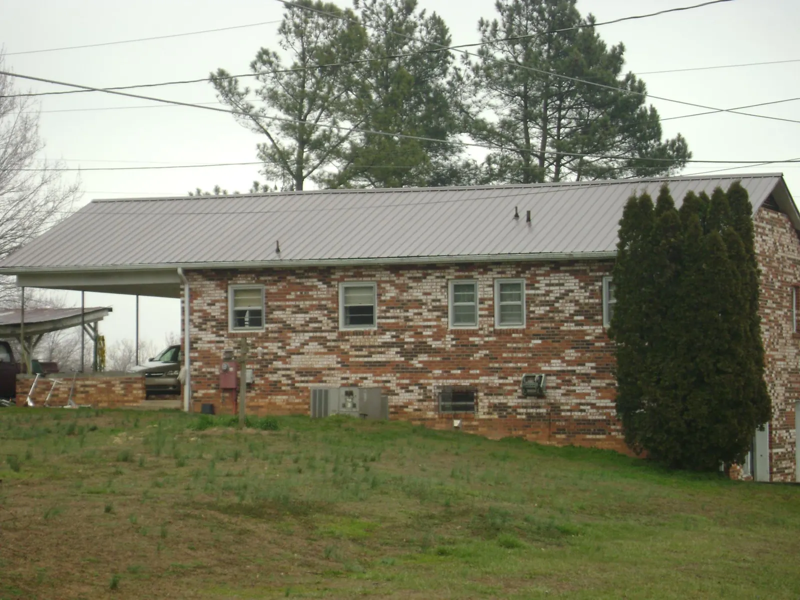Gray metal roof on a brick split level home with a carport in Howell