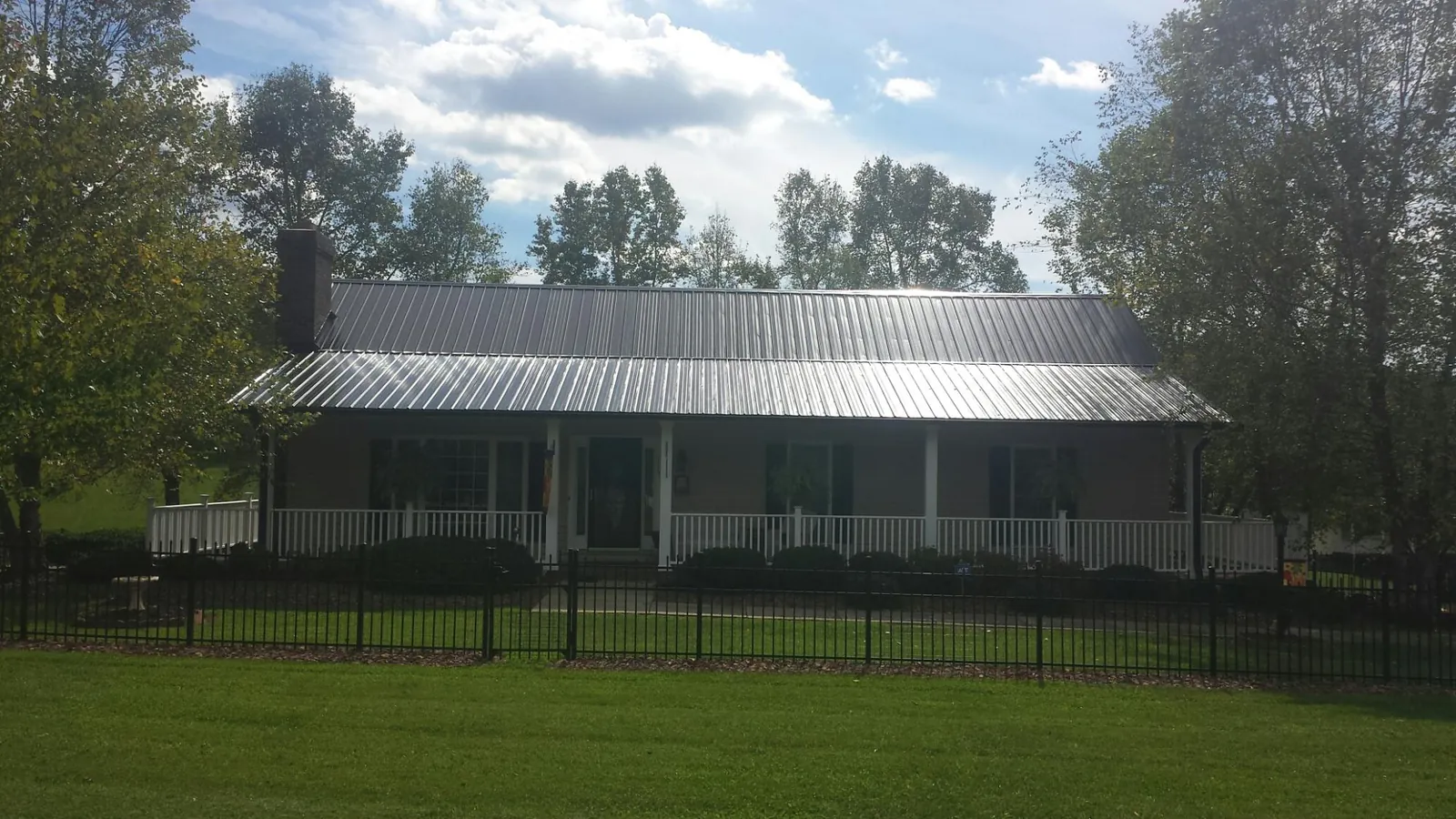 Gray metal roof on a brick ranch with a full width front porch — Gutter Guard Installation work by our crew in Howell