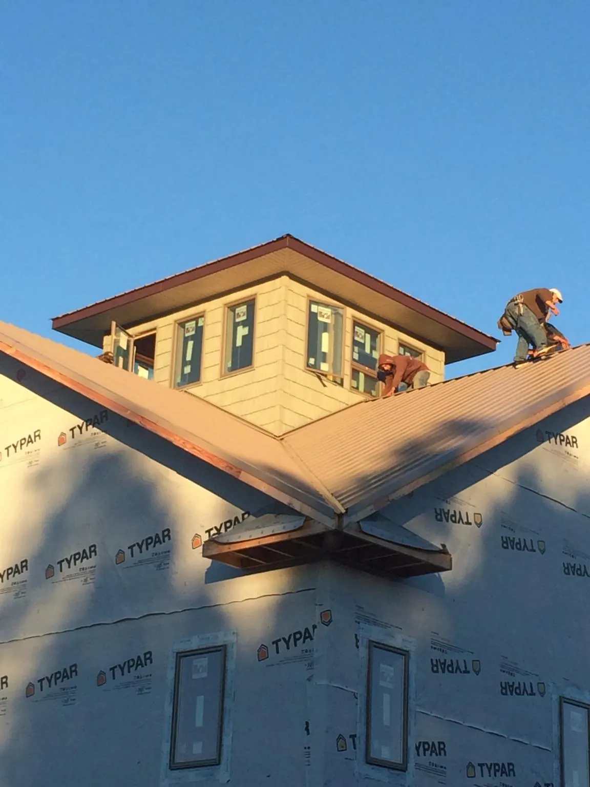 Roofers working around a rooftop cupola on a new metal roof at sunset — Roof Waterproofing in Howell by Roofing Brothers